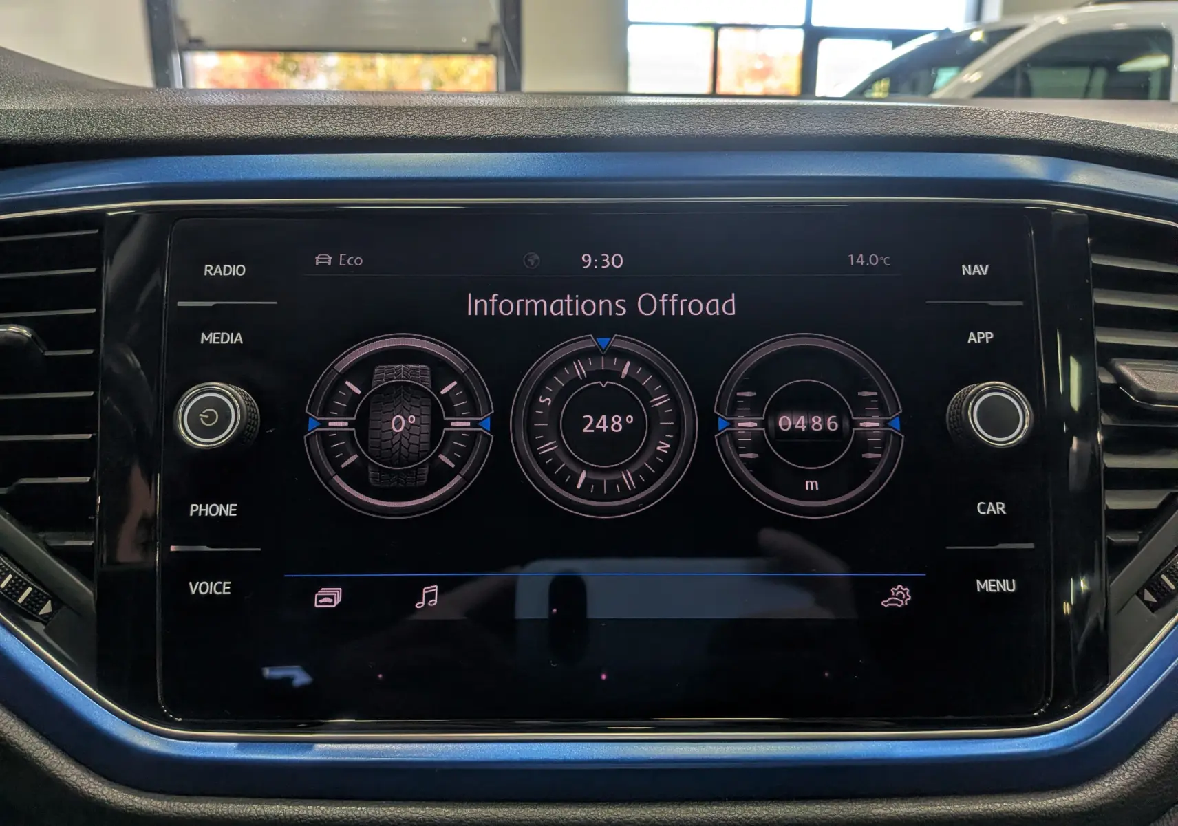 Écran central tactile du Volkswagen T-Roc 2018 affichant les informations offroad, entouré de touches et d'un cadre bleu Ravenna.