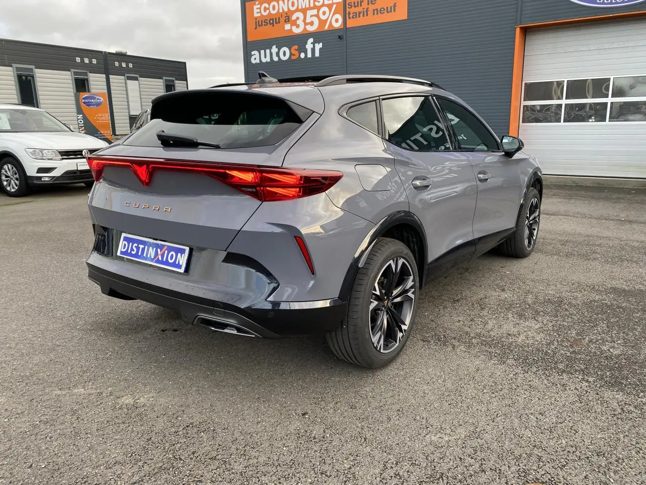 Vue 3/4 arrière droite d'un CUPRA Formentor gris Graphène avec jantes noires et feux arrière LED allumés.