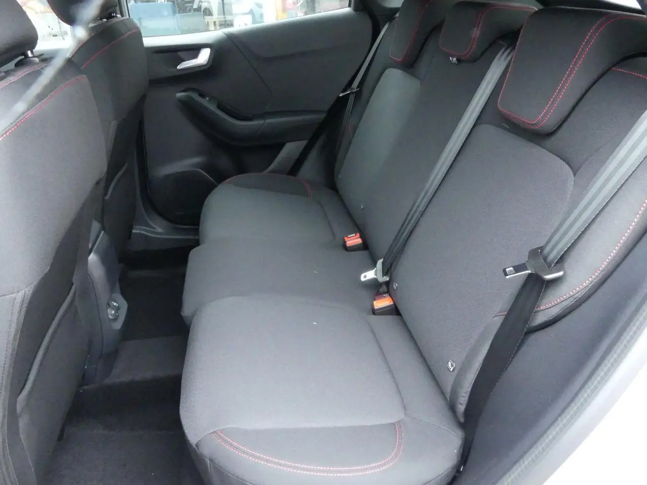 Vue côté droit de la banquette arrière noire avec surpiqûres rouges du Ford Puma 2025 gris métallisé.