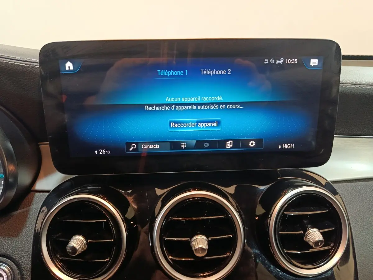 Écran tactile central et trois aérateurs ronds chromés du tableau de bord du Mercedes GLC bleu, vue intérieure frontale.