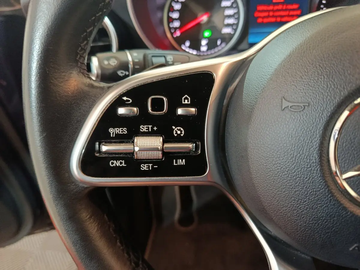 Gros plan sur les commandes de régulateur de vitesse au volant cuir d'une Mercedes GLC hybride rechargeable 2021.