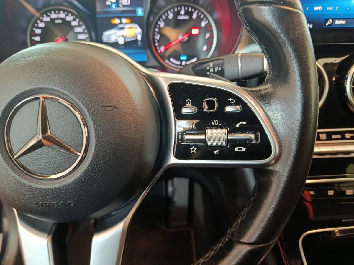 Gros plan sur le volant cuir noir de la Mercedes GLC 300 E Business Line 2021 avec commandes multifonctions et tableau de bord lumineux.