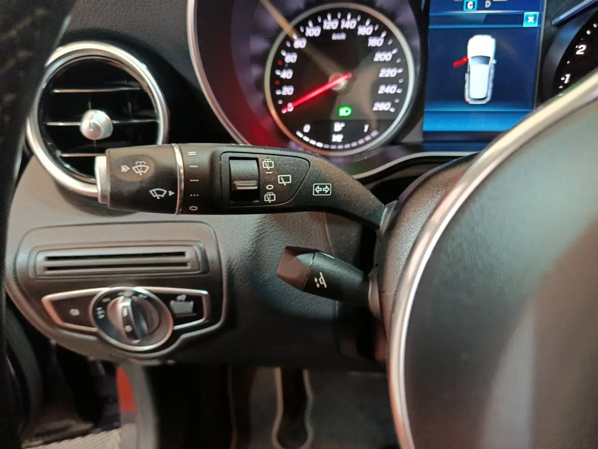 Gros plan sur la colonne de direction et le tableau de bord du Mercedes GLC bleu, avec commandes essuie-glaces et affichage digital.