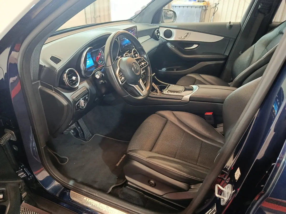 Intérieur côté conducteur d'un Mercedes GLC 300 E Business Line 2021 bleu, avec tableau de bord digital et sièges cuir noirs.