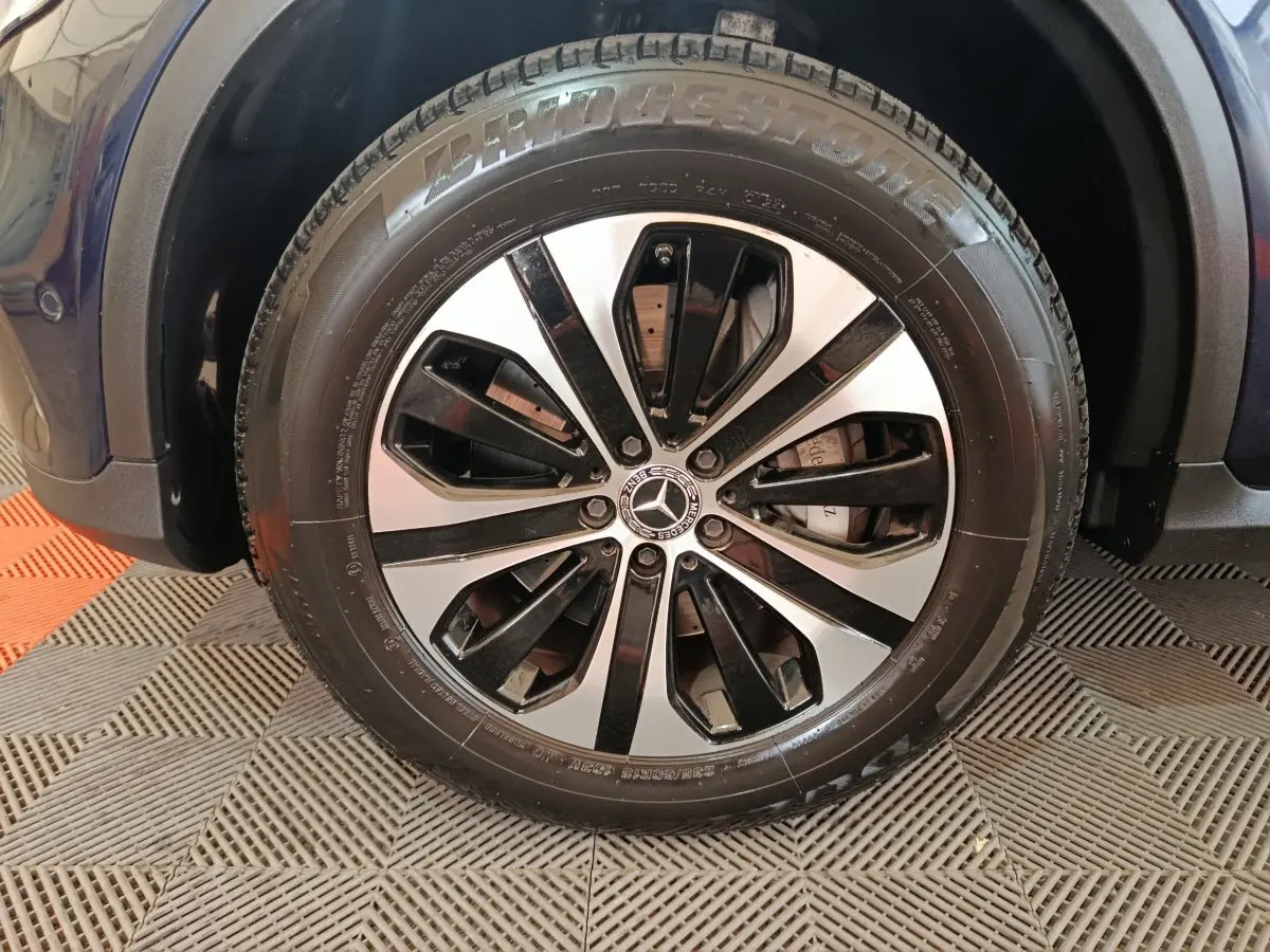 Gros plan sur la roue avant droite bleu Mercedes GLC 300 E avec jante alliage bicolore et pneu Bridgestone.