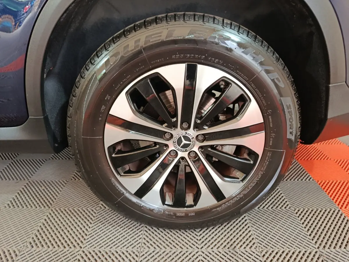 Gros plan sur la roue arrière droite d'un Mercedes GLC 300 E Business Line bleu, avec pneu sport visible.