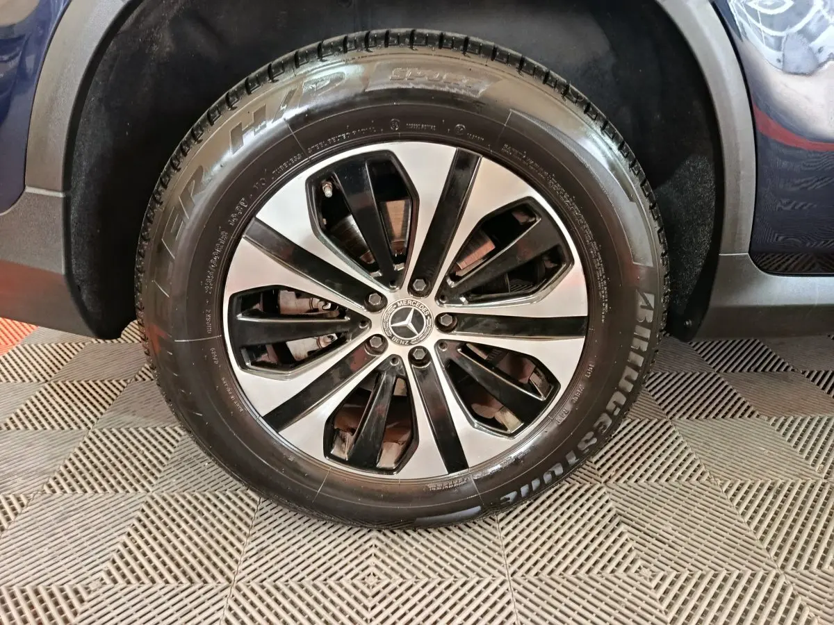 Gros plan sur la roue avant droite du Mercedes GLC bleu 2021 avec jante alliage bicolore et pneu Bridgestone.