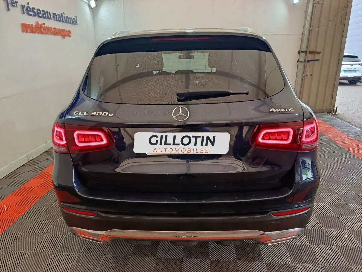 Vue arrière d'un Mercedes GLC 300e 4MATIC bleu avec feux LED allumés dans un showroom.
