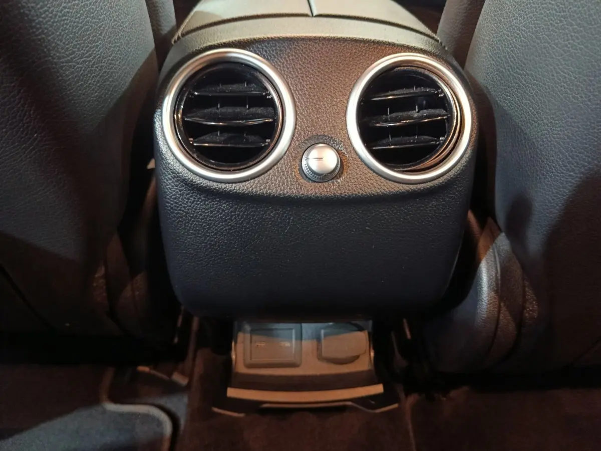 Détail des aérateurs arrière noirs avec bord chromé et commandes de ventilation dans un Mercedes GLC 300 E bleu.