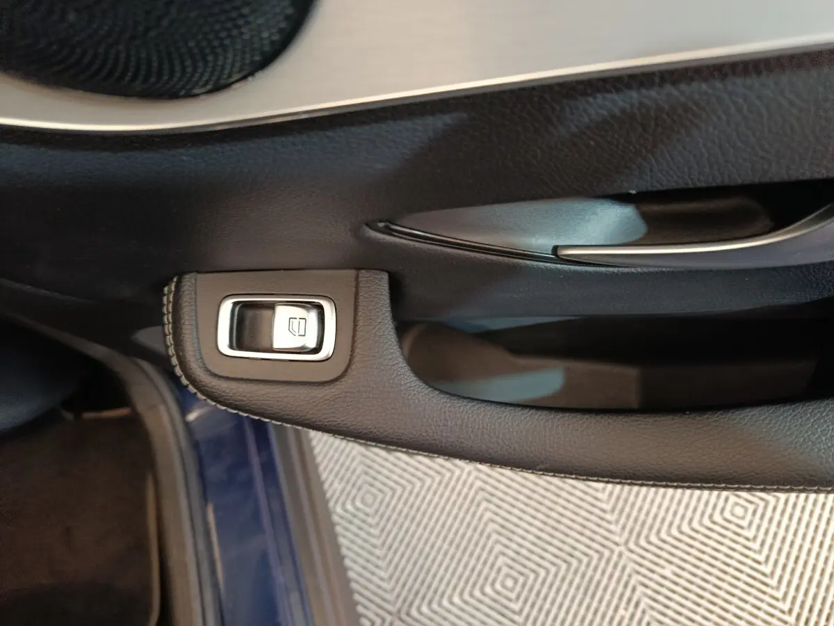 Détail de la commande de lève-vitre sur la porte côté conducteur d'un Mercedes GLC 300 E Business Line bleu.