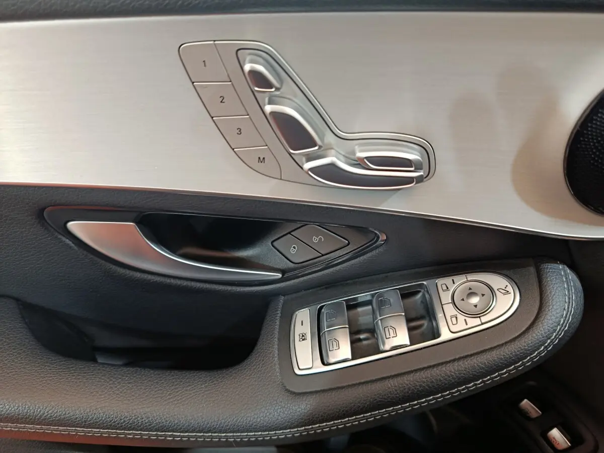 Gros plan sur la porte côté gauche du Mercedes GLC bleu, avec commandes de sièges et vitres en aluminium brossé.