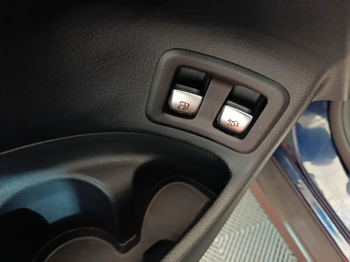 Boutons d'ouverture du coffre et de la trappe à carburant sur la porte côté conducteur d'un Mercedes GLC bleu 2021.