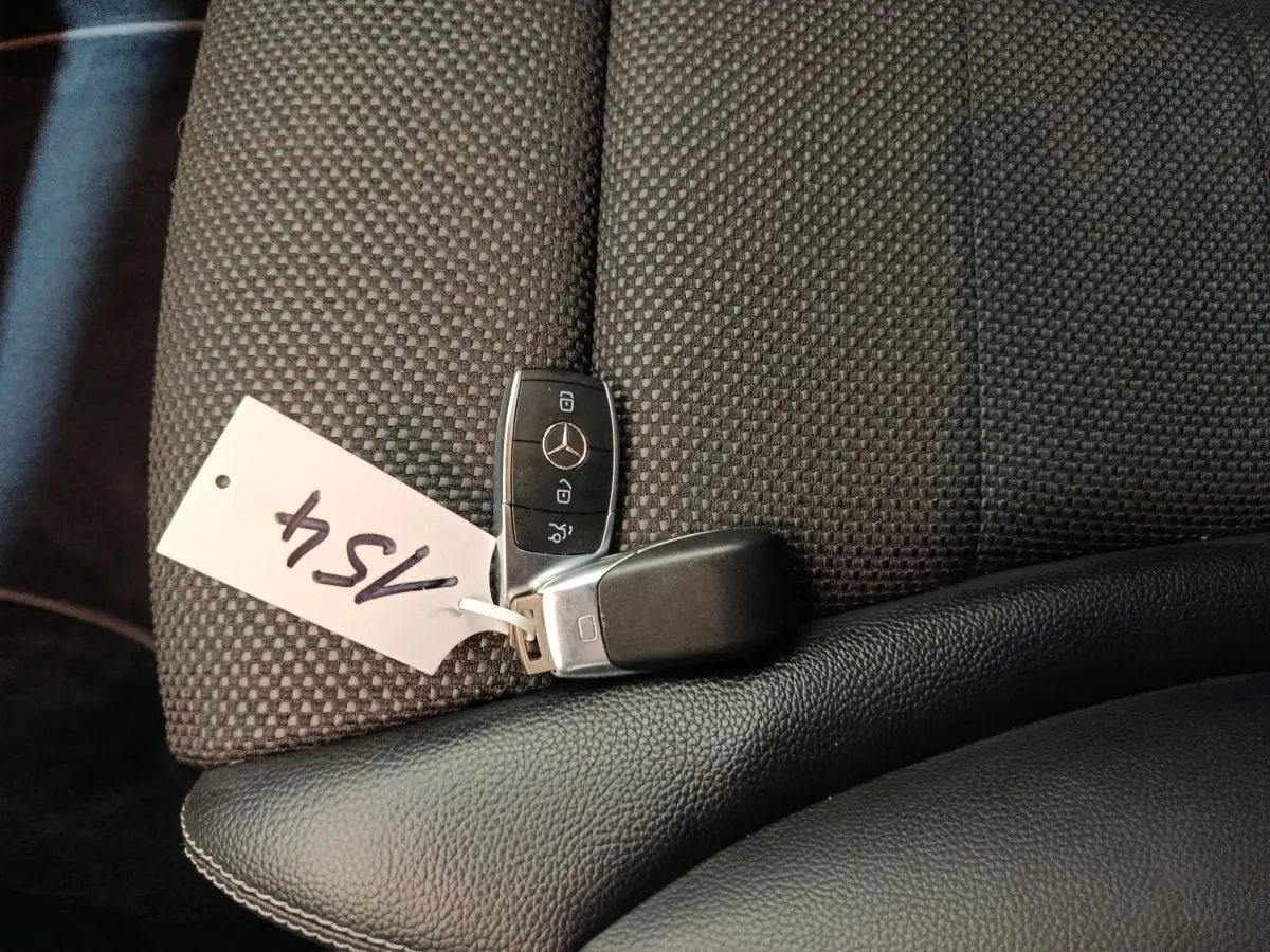 Clé Mercedes posée sur un siège tissu gris foncé avec appui-coude en cuir noir dans un GLC 300 E Business Line 2021.