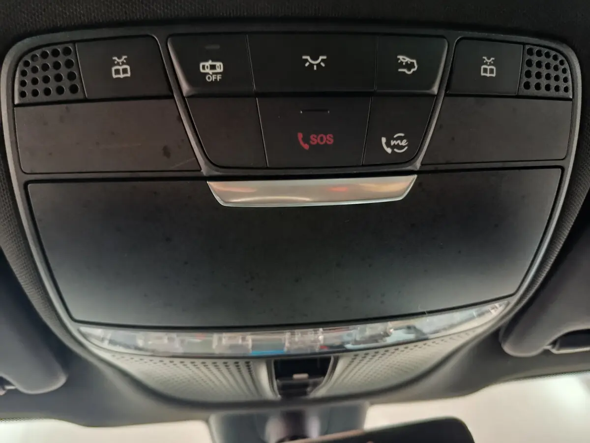 Vue en gros plan du panneau de commande au plafond du Mercedes GLC 300 E Business Line bleu, avec bouton SOS rouge et commandes d'éclairage.