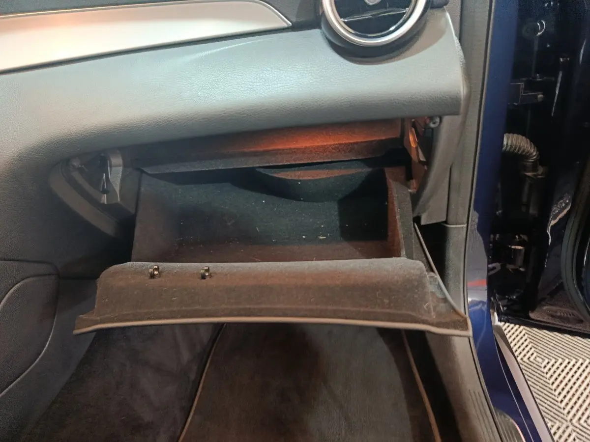 Vue rapprochée de la boîte à gants ouverte côté passager d'un Mercedes GLC 300 E Business Line bleu 2021.