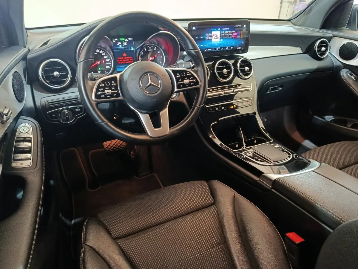 Intérieur noir du Mercedes GLC 300 E Business Line 2021 vu côté conducteur, tableau de bord et écran tactile central visibles.