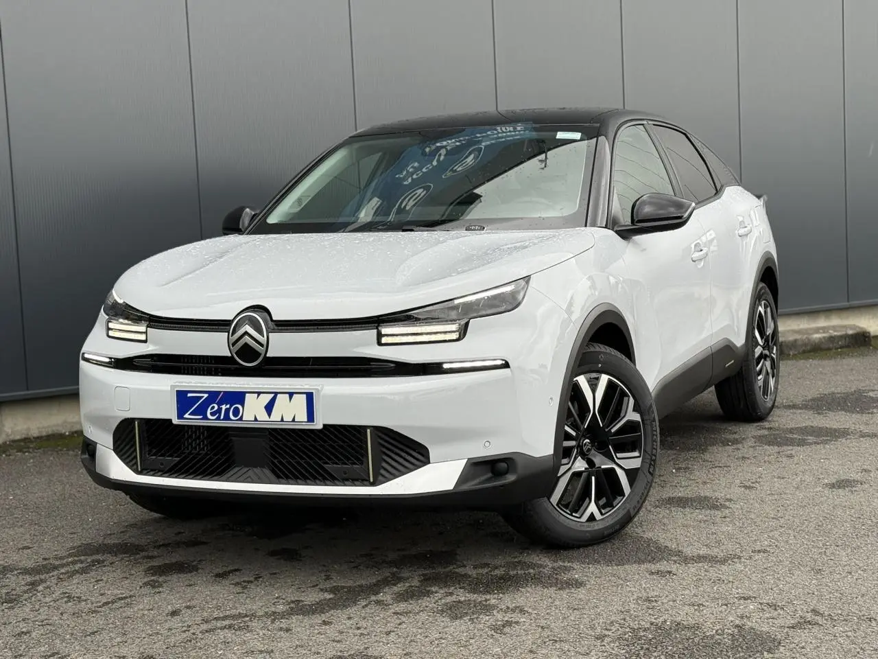 Citroën C4 hybride blanc Okénite avec toit noir, vue 3/4 avant mettant en valeur ses phares LED et jantes 18 pouces.