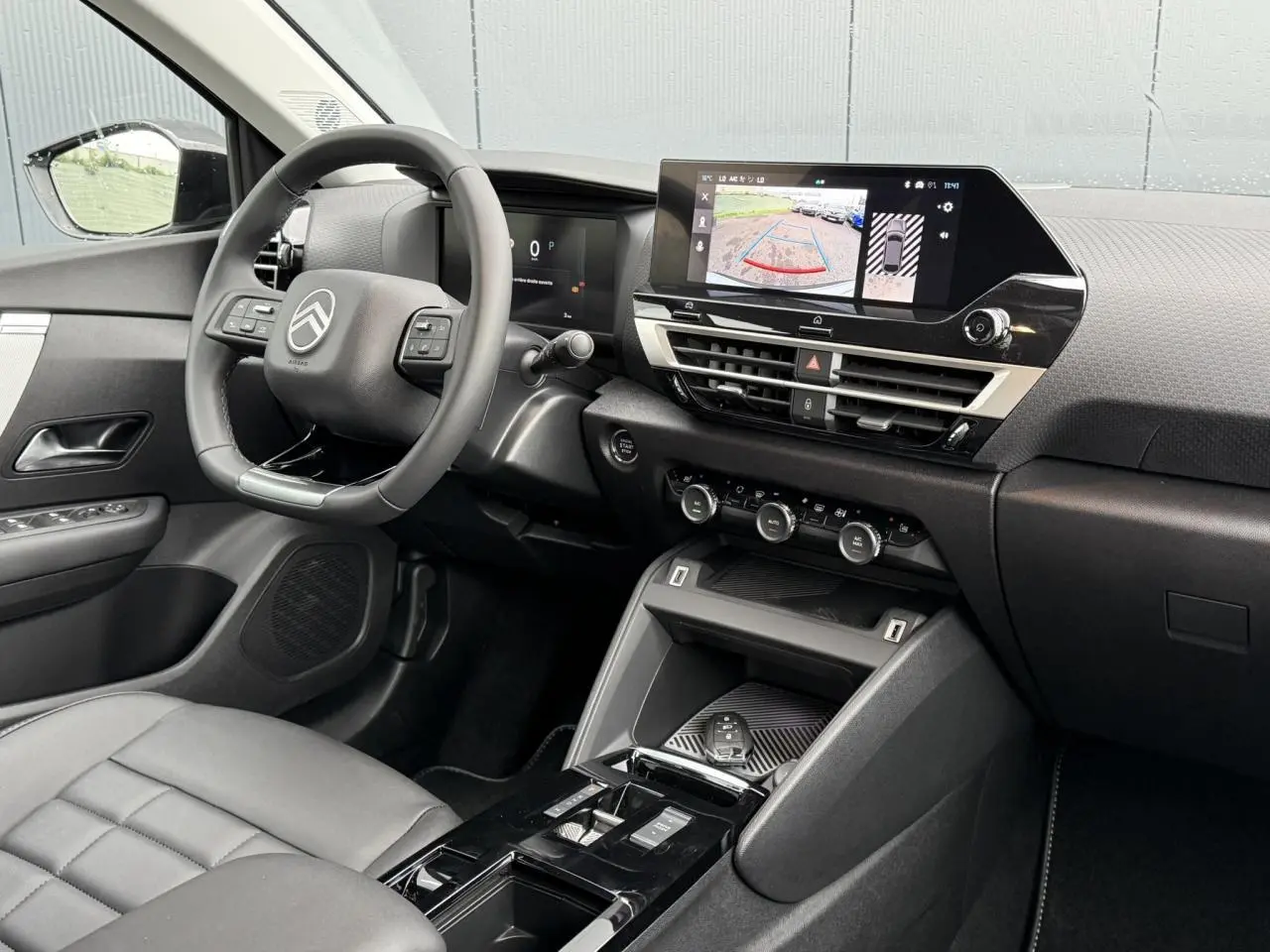 Vue intérieure côté conducteur de la Citroën C4 hybride 2025 avec écran tactile affichant la caméra de recul.