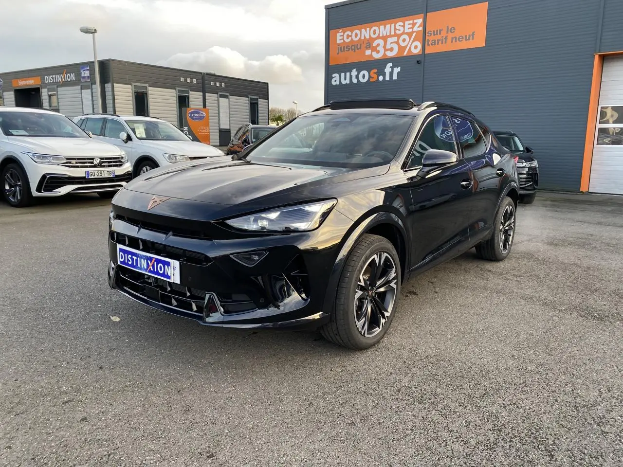 CUPRA Formentor noir Midnight en 3/4 avant droit, jantes sport bicolores, stationné devant un bâtiment commercial.