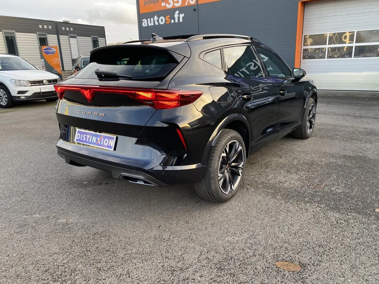 Vue 3/4 arrière droite d'un CUPRA Formentor noir Midnight avec jantes 18 pouces Sonora et feux arrière allumés.