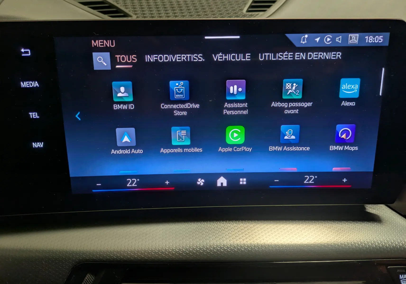 Écran tactile central du BMW X1 blanc 2025 affichant le menu principal avec options connectées et climatisation à 22°C.