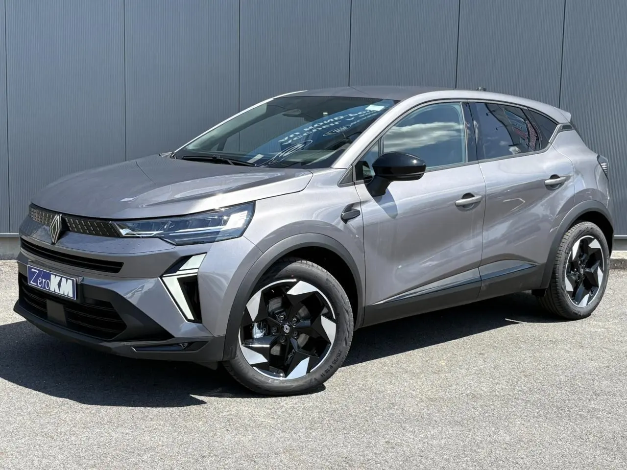 Renault Captur gris Cassiopée en 3/4 avant droit, avec jantes noires et phares LED distinctifs.