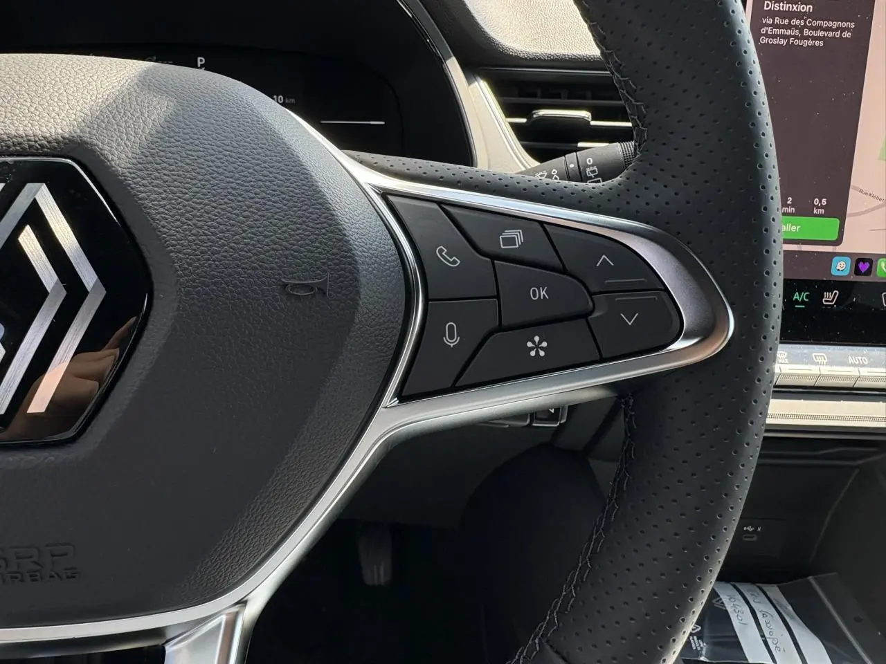 Gros plan sur le volant cuir multifonctions du Renault Captur gris Cassiopée avec commandes intégrées et écran tactile visible.