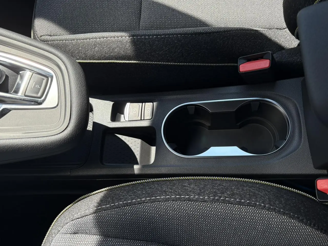 Gros plan sur la console centrale du Renault Captur gris Cassiopée, avec porte-gobelets et commandes de frein électrique.