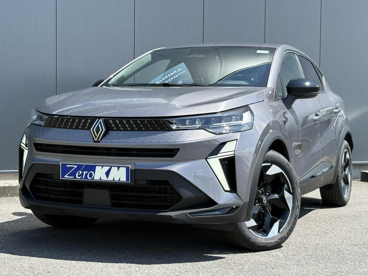 Renault Captur gris Cassiopée en 3/4 avant droit, avec calandre noire et jantes aluminium 18 pouces noires et argentées.