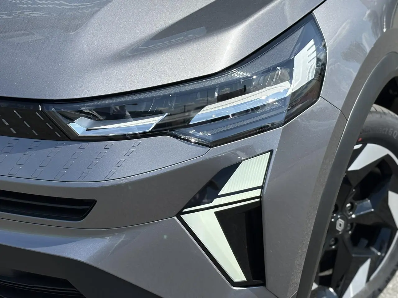 Gros plan sur l'avant droit du Renault Captur gris Cassiopée, mettant en valeur ses phares LED et jante aluminium 18 pouces.