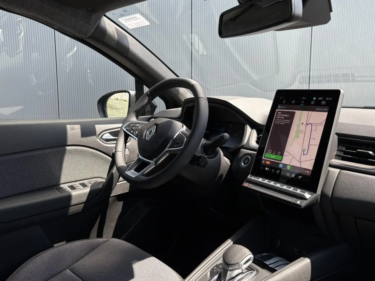 Intérieur du Renault Captur hybride 2025 côté conducteur, volant cuir multifonctions et écran tactile vertical avec navigation.