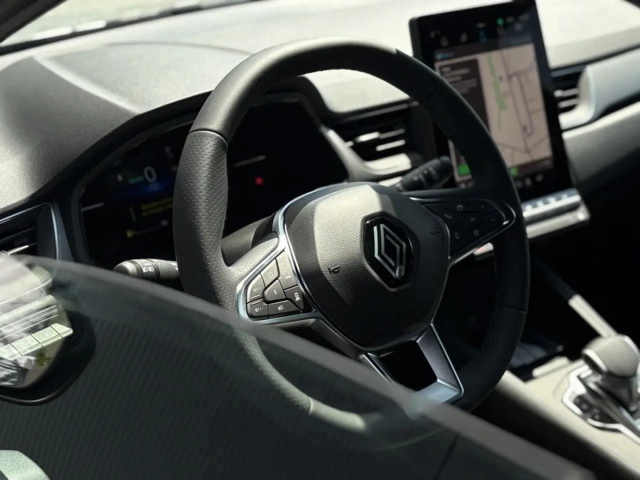 Gros plan sur le volant cuir multifonctions Renault Captur 2025 avec tableau de bord et écran tactile visible en arrière-plan.