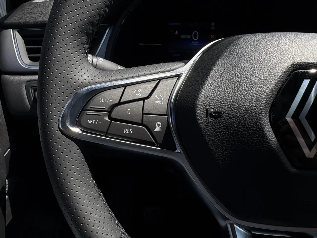 Gros plan sur le volant cuir multifonctions du Renault Captur 2025, avec commandes du régulateur adaptatif visibles.