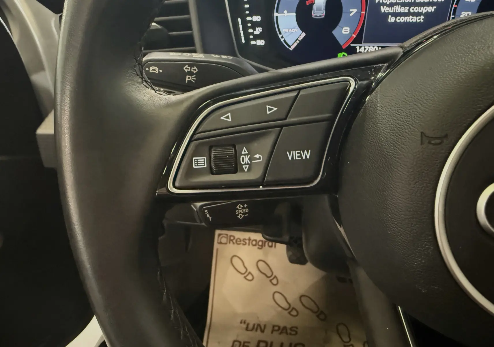 Gros plan sur le volant multifonction de l'Audi A1 30 TFSI blanche, avec affichage numérique du tableau de bord en arrière-plan.