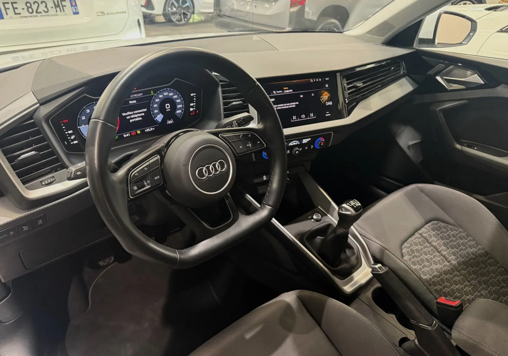 Intérieur Audi A1 30 TFSI 2024 vu côté conducteur, volant cuir, tableau de bord digital et levier de vitesse manuel.