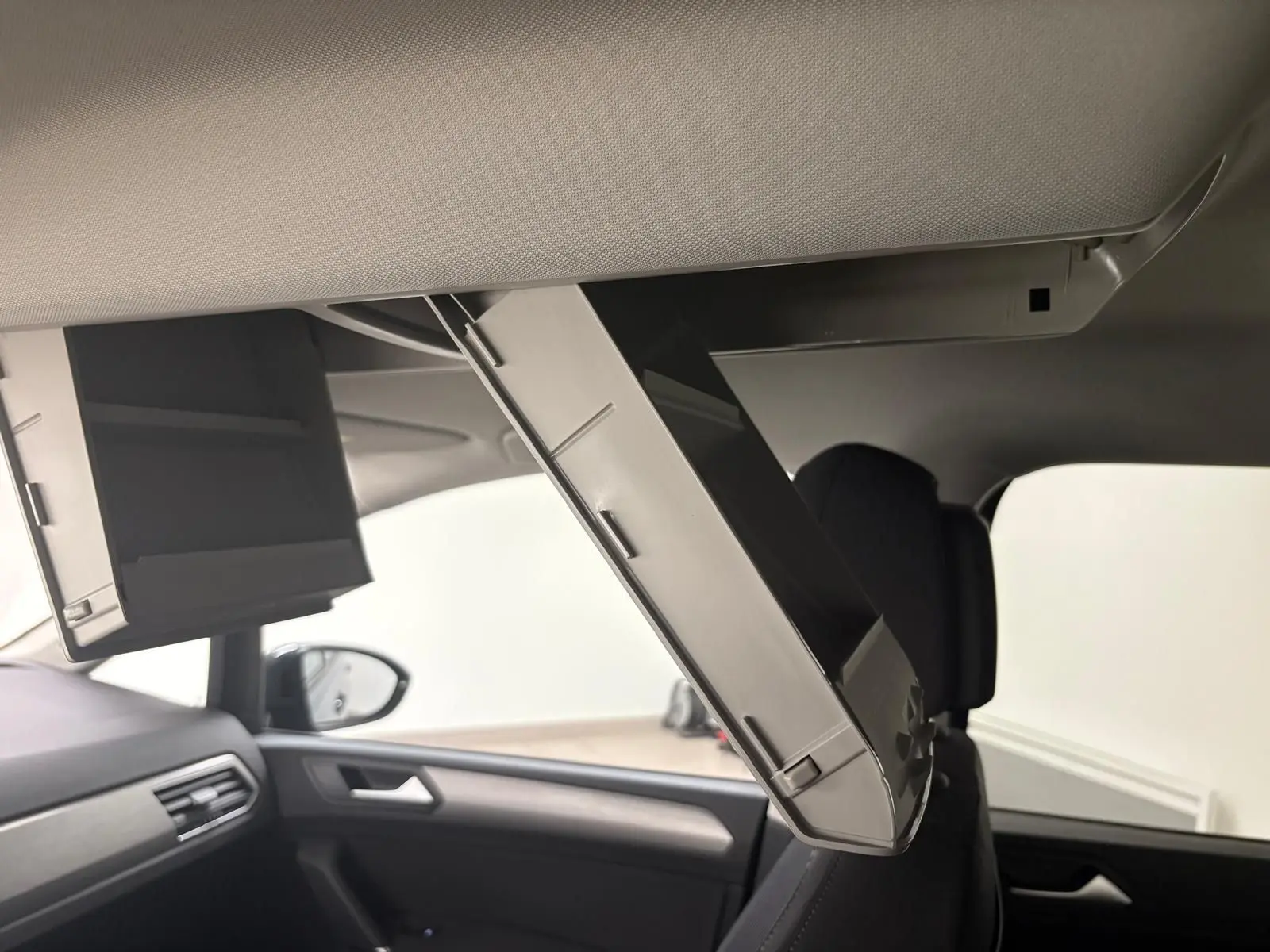 Détail de l'écran rabattable pour passagers arrière dans l'habitacle du Volkswagen Touran gris dauphin 2025.