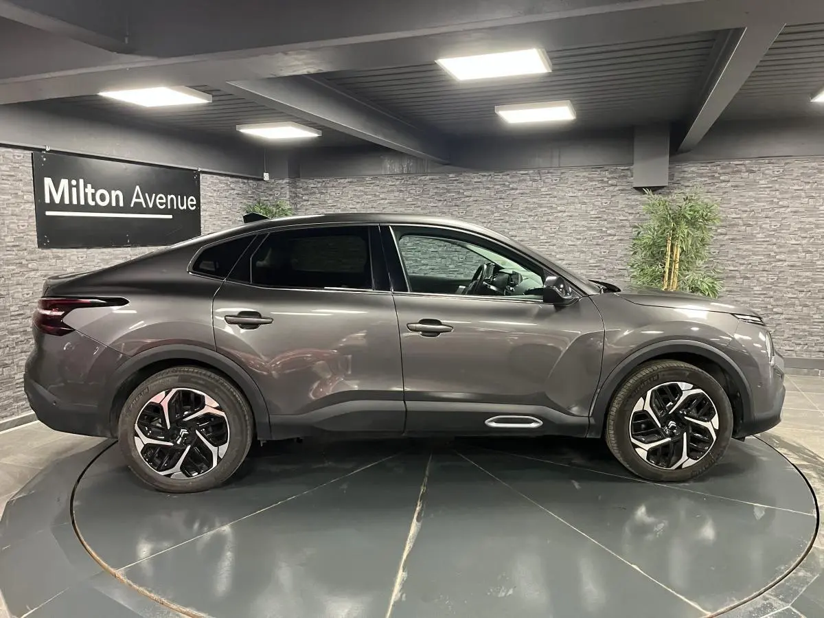 Profil côté droit d'une Citroën C4 2024 gris métallisé avec jantes alliage 18'' et lignes fluides modernes.