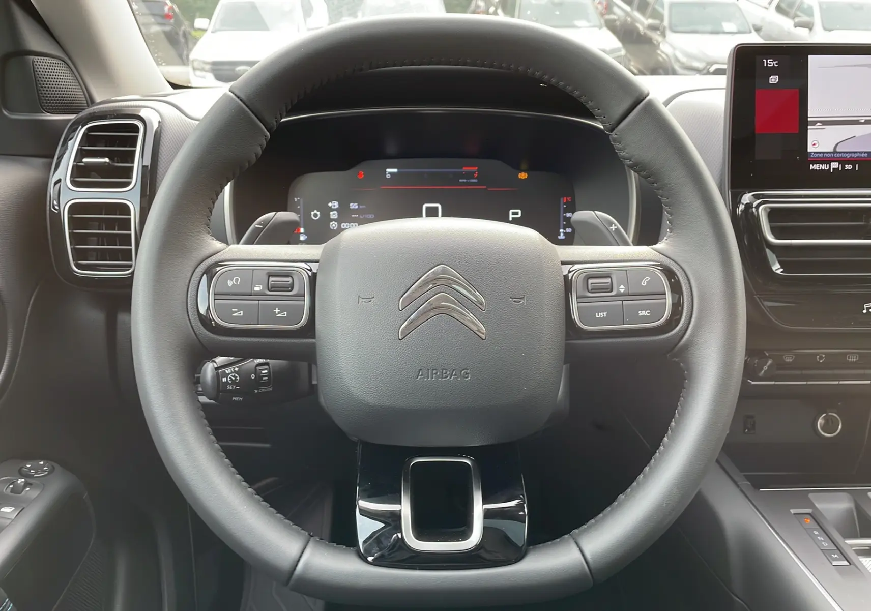 Vue rapprochée du volant noir et du tableau de bord numérique du Citroën C5 Aircross Hybrid 2025 avec commandes intégrées.