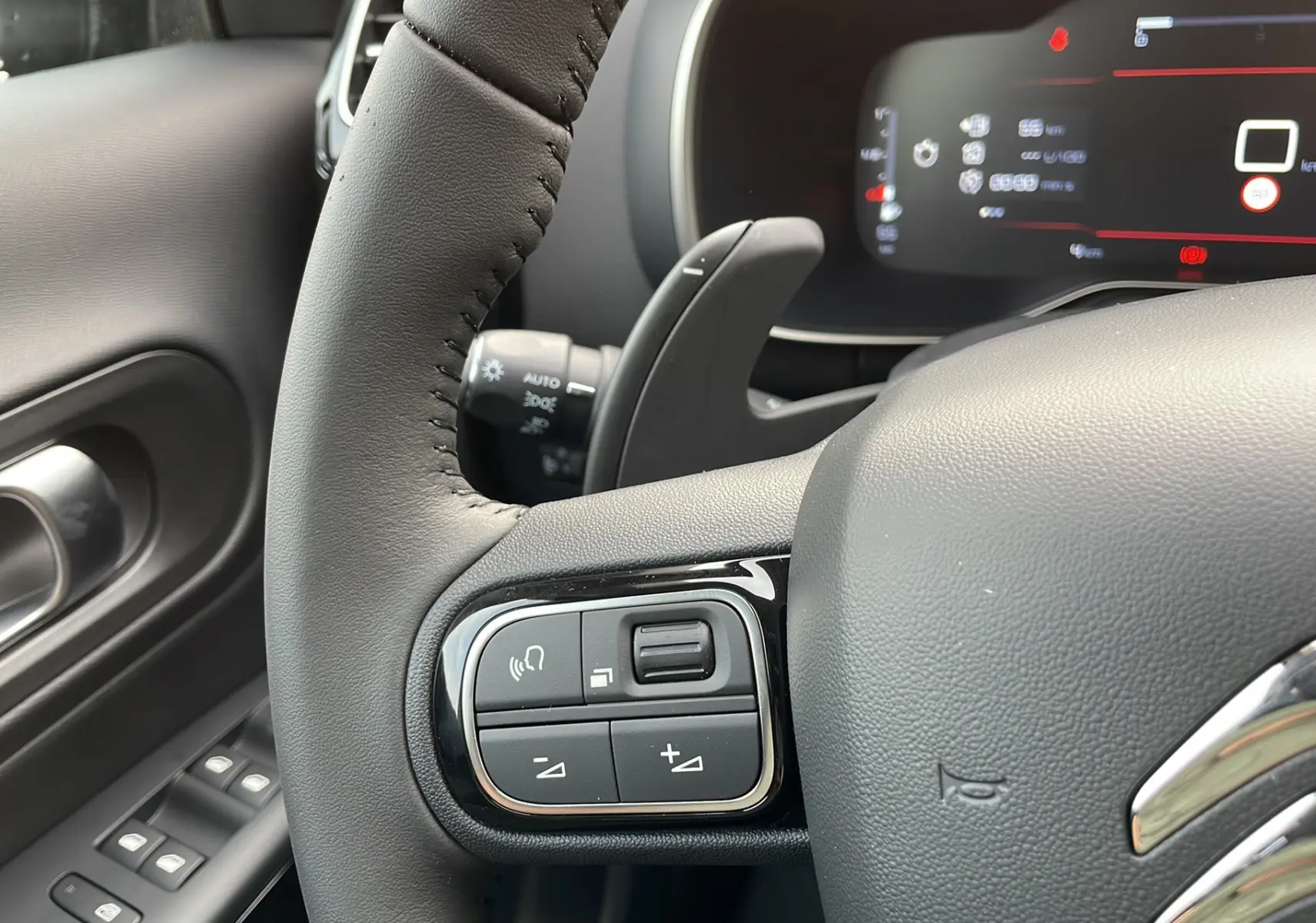 Gros plan sur le volant noir du Citroën C5 Aircross Hybrid 2025 avec commandes intégrées et tableau de bord numérique.