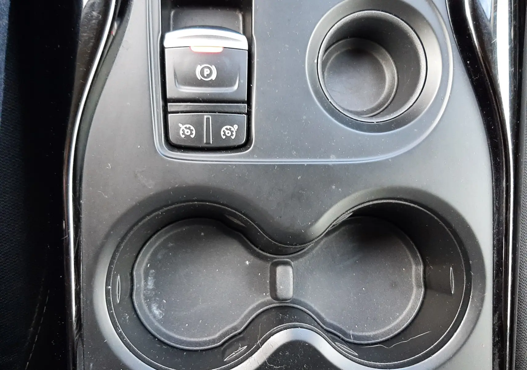 Gros plan sur la console centrale noire du Renault Kadjar 2018, avec porte-gobelets et commande de frein à main électrique.