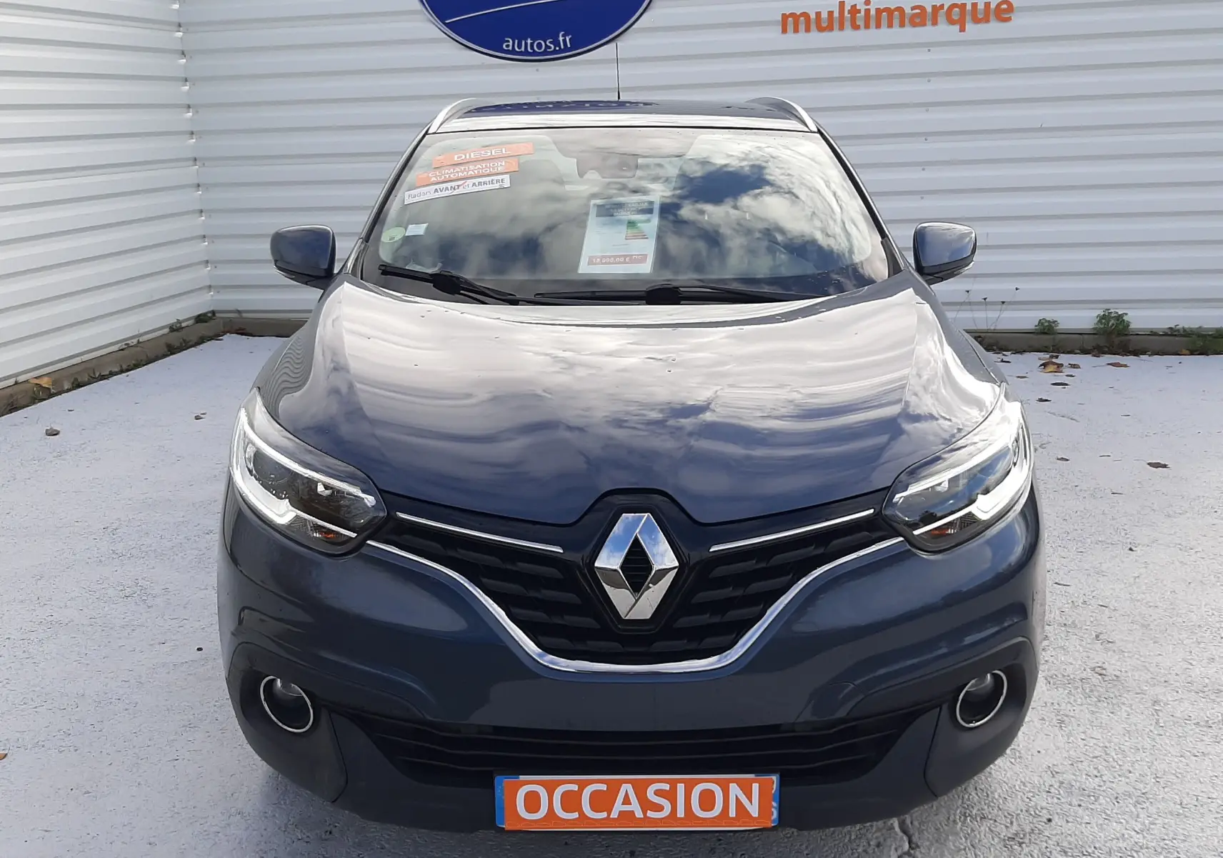 Vue frontale d'un Renault Kadjar gris 2018 avec phares allumés et plaque "OCCASION" visible sur un parking.