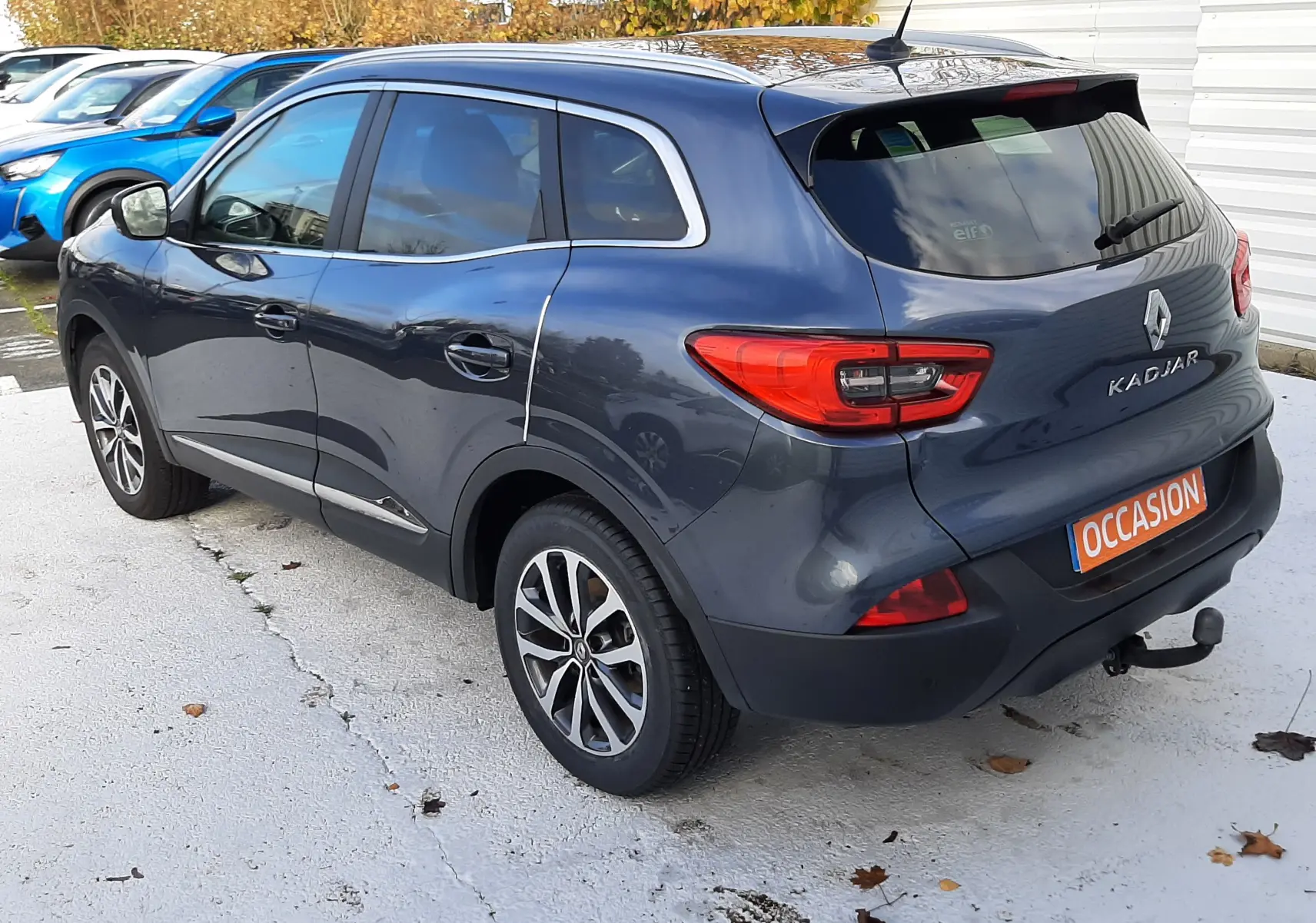 Vue 3/4 arrière droite d'un Renault Kadjar gris 2018 avec feux LED et attelage visible sur un parking.