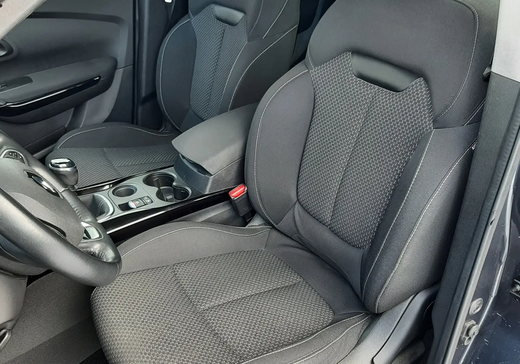 Vue intérieure côté conducteur du Renault Kadjar gris 2018, sièges tissu gris foncé avec coutures contrastées.