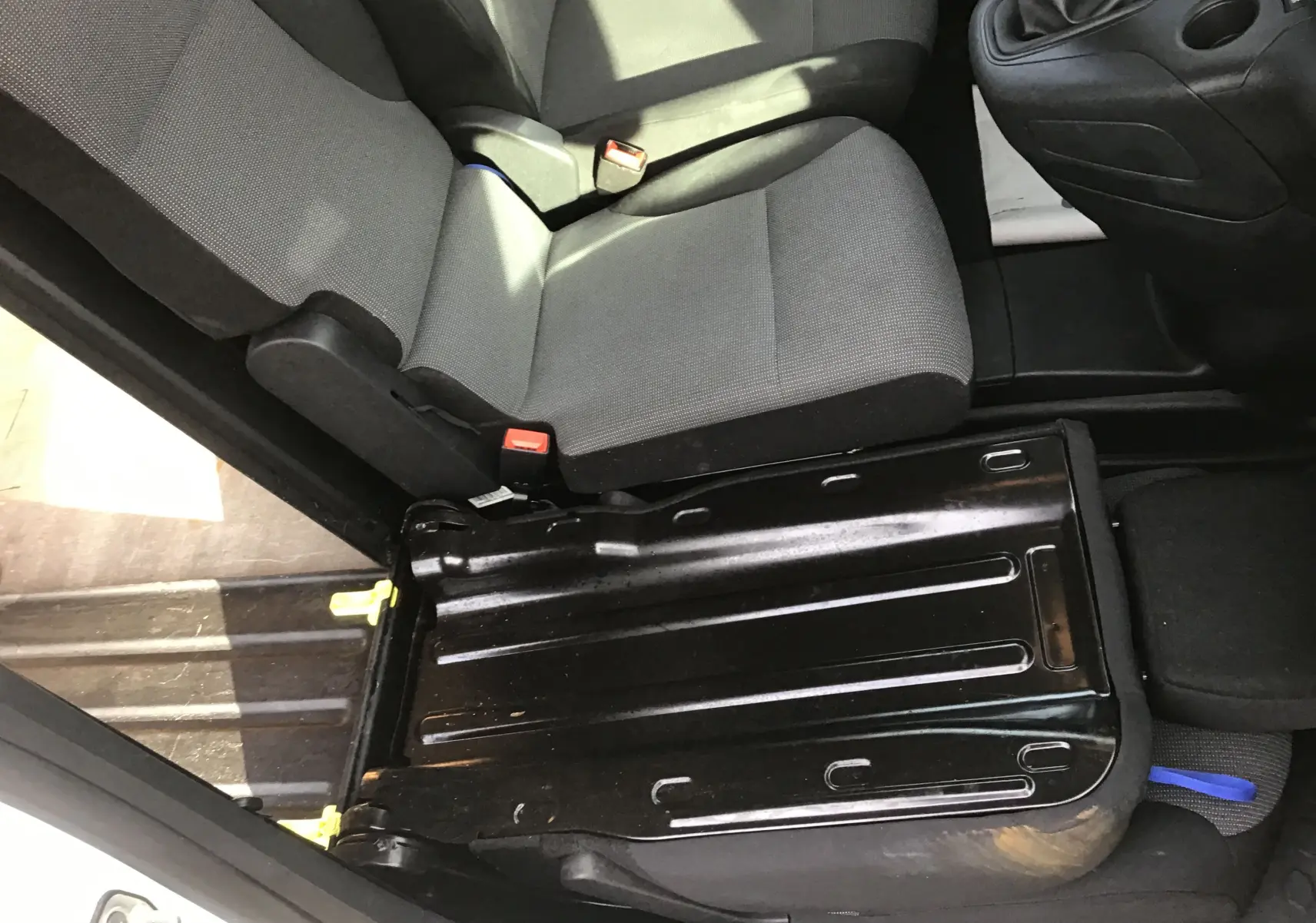 Vue intérieure côté gauche du siège avant gris du Citroën Berlingo blanc, montrant la base métallique du siège relevée.