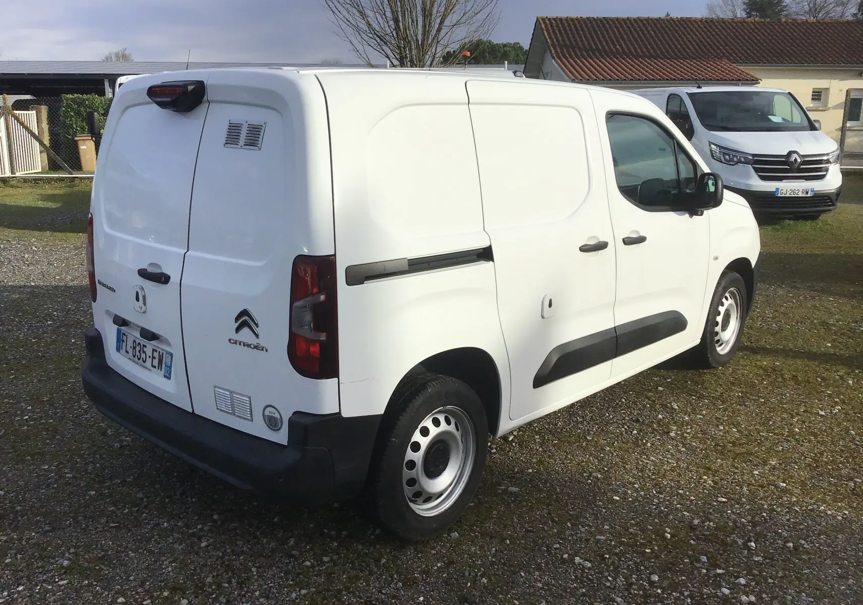 Vue 3/4 arrière droite d’un utilitaire Citroën Berlingo blanc de 2019 avec portes arrière battantes et protections latérales noires.