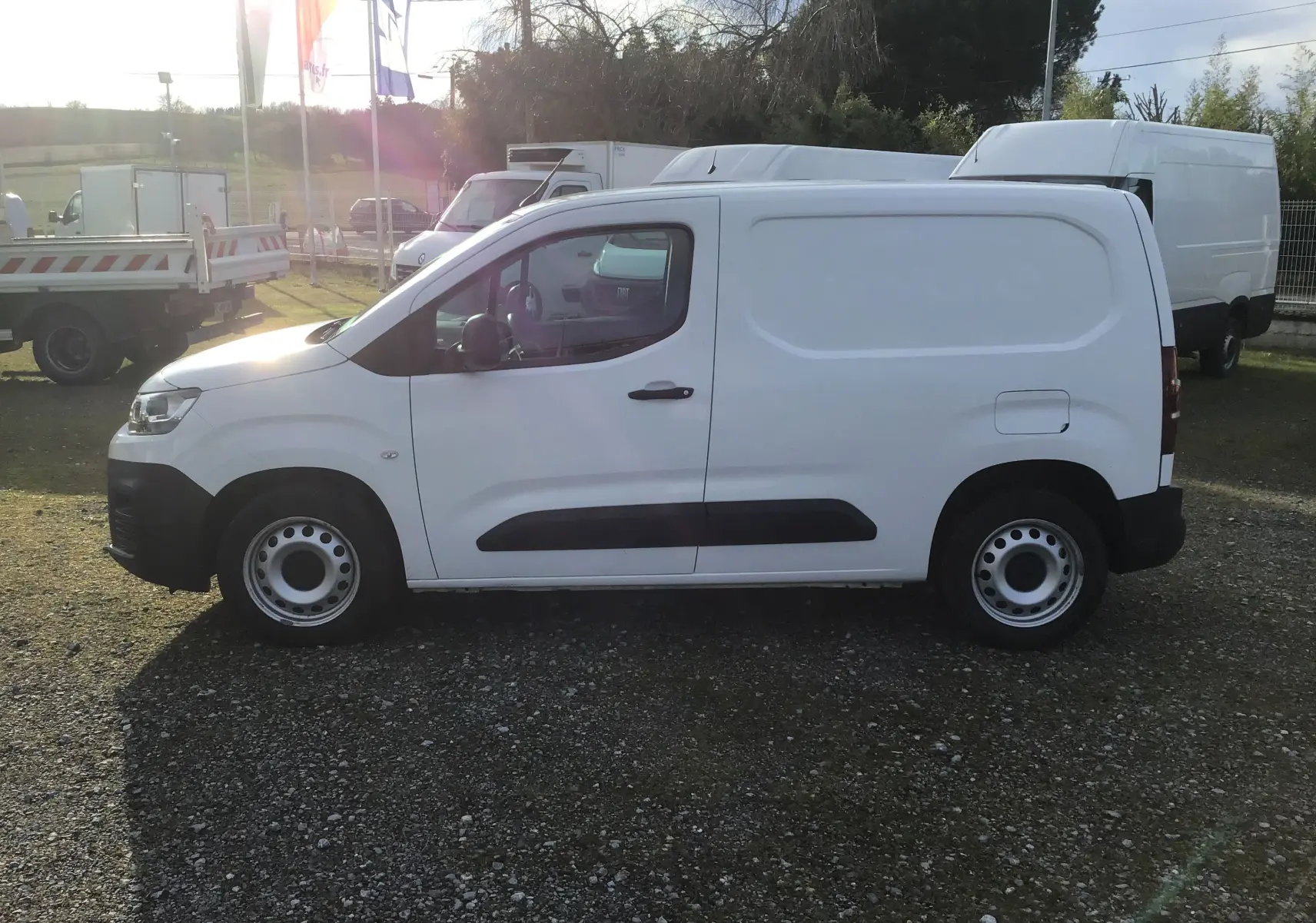 Vue de profil côté gauche d’un utilitaire Citroën Berlingo blanc, avec porte latérale pleine et jantes acier.