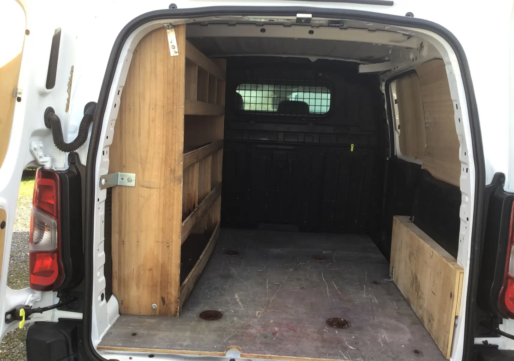 Vue arrière intérieure du Citroën Berlingo blanc 2019 avec aménagements bois pour rangement et protection des parois.