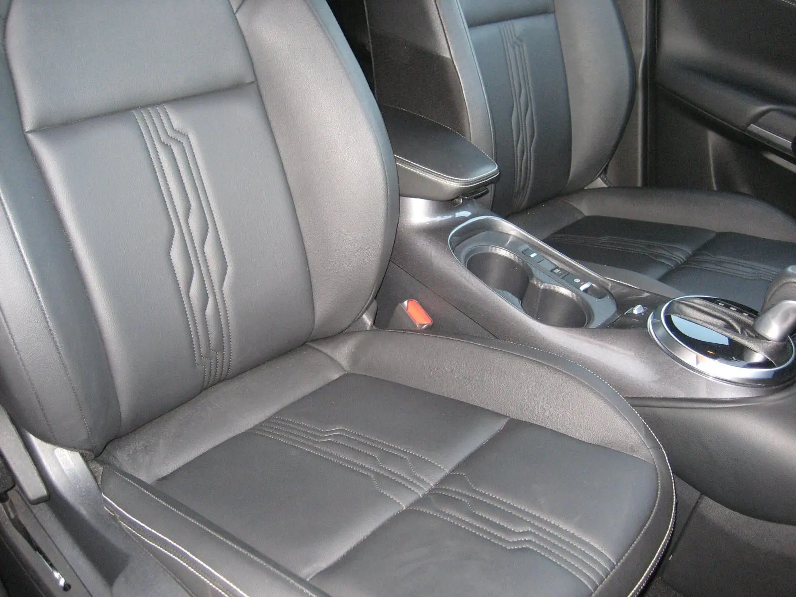 Gros plan sur les sièges avant en cuir noir et la console centrale du Nissan Juke 1.6 Hybrid 143 Tekna 2024.