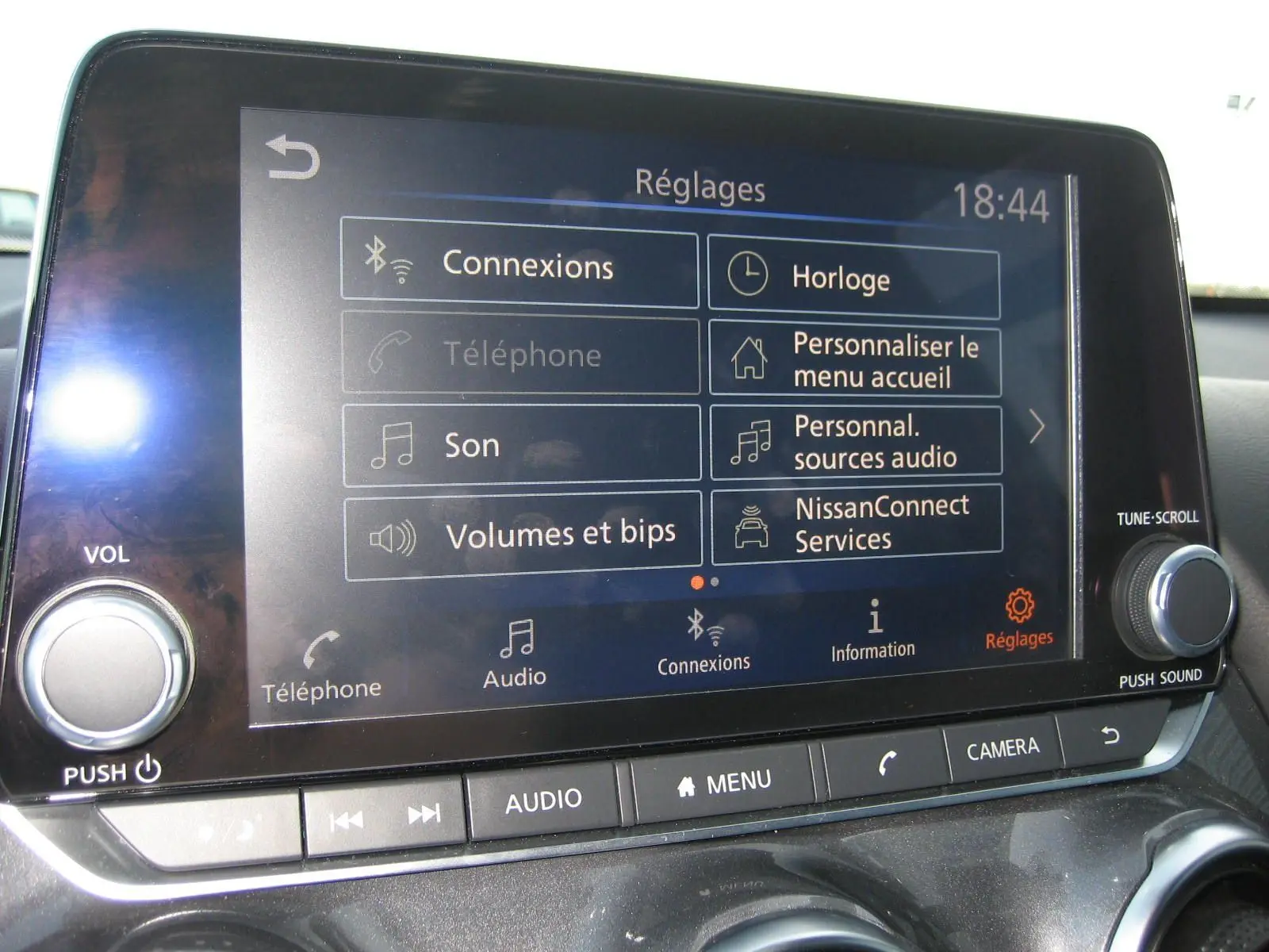 Écran tactile central du Nissan Juke 2024 en gros plan, affichant le menu des réglages audio et connexions.