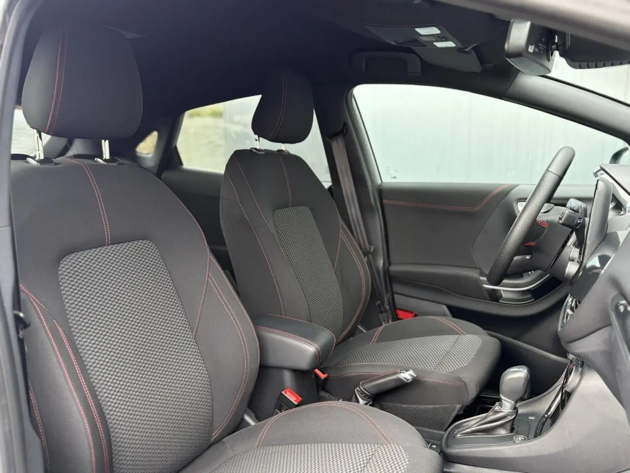 Vue intérieure côté droit du Ford Puma 2023 ST Line, sièges noirs avec surpiqûres rouges et console centrale avec boîte auto.
